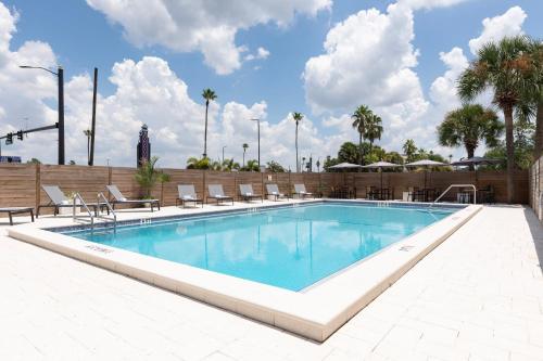 a large swimming pool with chairs and a fence at The Vietta Hotel in Kissimmee