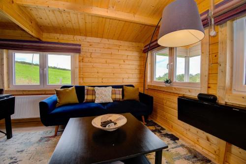 a living room with a blue couch and a table at Luxury Log Cabin with Private Hot Tub & Sea Views in Letterkenny