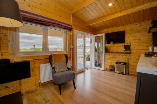 a room with a chair and a television in a room at Luxury Log Cabin with Private Hot Tub & Sea Views in Letterkenny
