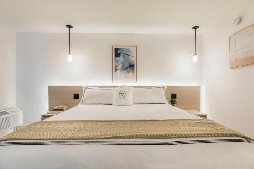 a bedroom with a large white bed with two pillows at The Vietta Hotel in Kissimmee