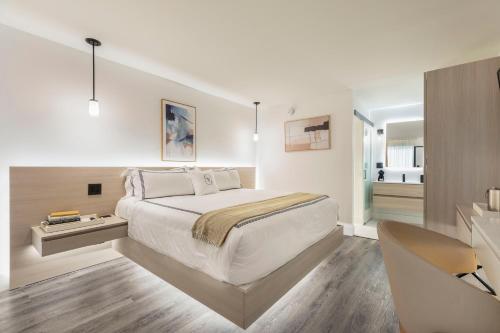 a bedroom with a large white bed and a bathroom at The Vietta Hotel in Kissimmee