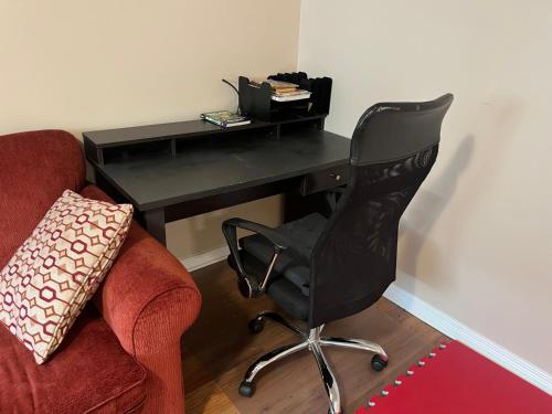 a black desk with a chair and a table with a laptop at Spacious and Charming Bungalow Retreat (Close to Many Amenities) in Kingston