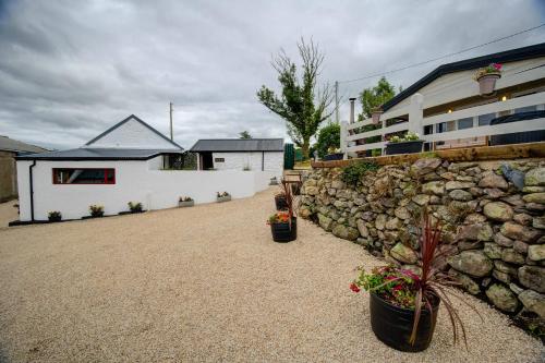 a stone wall next to a house with potted plants at Luxury Log Cabin with Private Hot Tub & Sea Views in Letterkenny