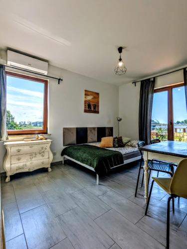 a bedroom with a bed and a table and windows at Słoneczna Sarbinówka in Sarbinowo