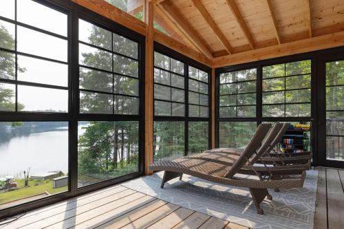 a screened in porch with a chair and windows at Muskoka Gem 8ppfireplacescanoekayaks in Bracebridge