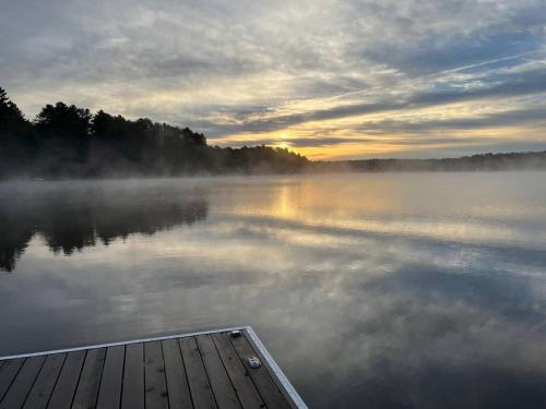 a boat on a lake with fog on the water at Muskoka Gem 8ppfireplacescanoekayaks in Bracebridge