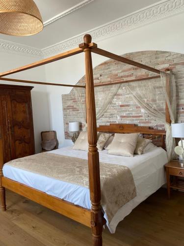 a bedroom with a wooden canopy bed with white sheets at Château de Saint-Genix in Saint-Genix-sur-Guiers