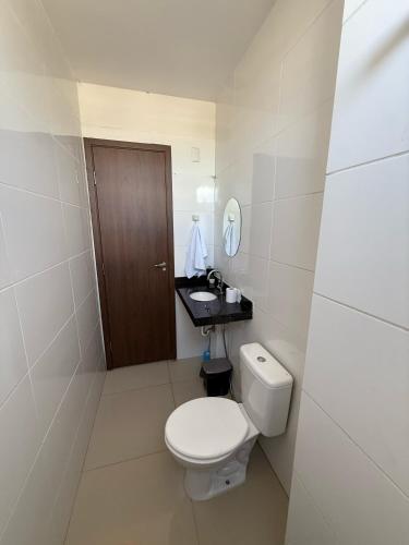 a white bathroom with a toilet and a sink at Apartamento Frente à Praia da Graciosa in Palmas