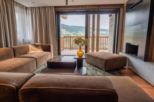 a living room with a couch and a large window at Hôtel L'Arboisie in Megève