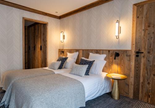 a hotel room with two beds and a table at Hôtel L'Arboisie in Megève