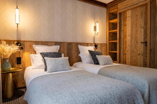 two beds in a room with wood paneling at Hôtel L'Arboisie in Megève
