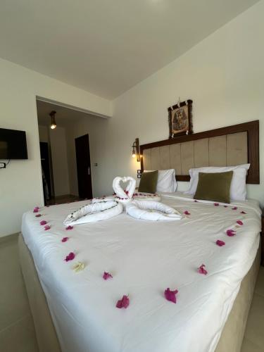 a large white bed with pink flowers on it at Are Pyramids View in Cairo