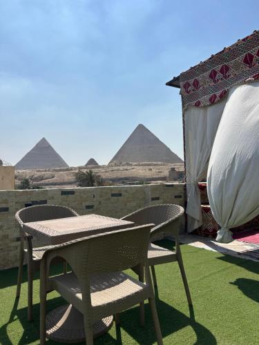 a table and chairs with the pyramids in the background at Are Pyramids View in Cairo