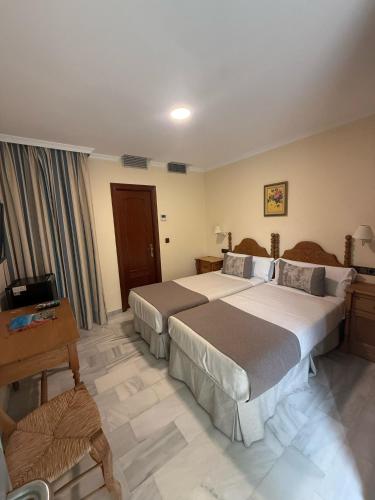 a hotel room with two beds and a television at Hotel La Española in Chipiona