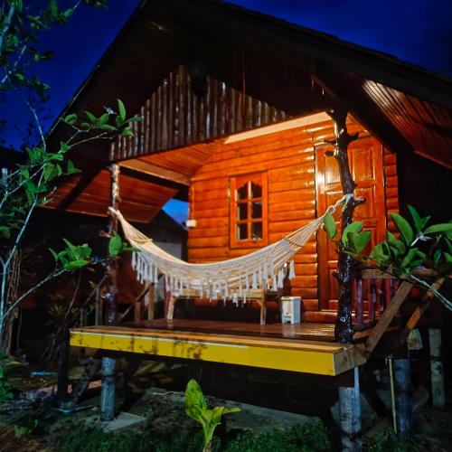 a hammock in front of a log cabin at TA YAI HOMESTAY (ตา ยาย โฮมสเตย์) in Ko Kood