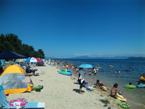 a crowd of people on a beach with umbrellas at Holiday Afternoon in Otsu