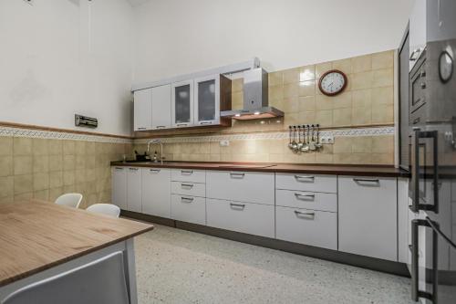 a kitchen with white cabinets and a clock on the wall at Casa Caraish Arucas Rooms in Arucas