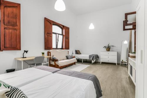 a bedroom with two beds and a desk and a chair at Casa Caraish Arucas Rooms in Arucas