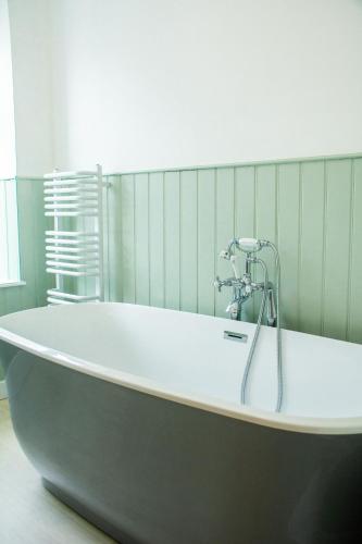 a bath tub with a faucet in a bathroom at Puffin Cottage in Beaumaris