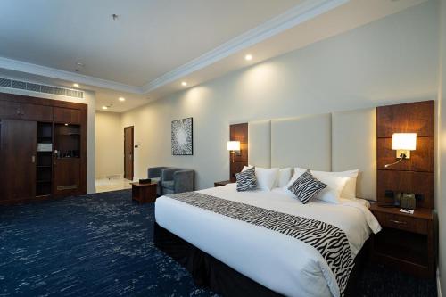 a hotel room with a large bed and a chair at Sunday Jeddah Hotel in Jeddah