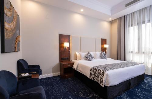 a hotel room with a bed and two chairs at Sunday Jeddah Hotel in Jeddah