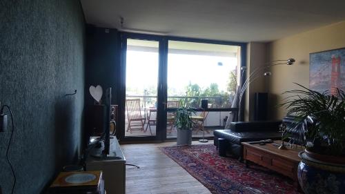a living room with a couch and a large window at Guestroom with wide view and pool near city side, 2nd guest with extra bed possible in Frankfurt/Main