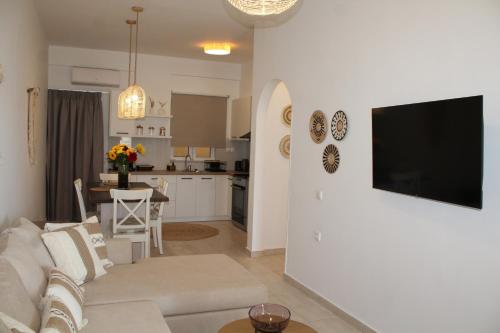 a living room with a couch and a television on a wall at Rena's Guesthouse, by Comfortbnb in Sitia