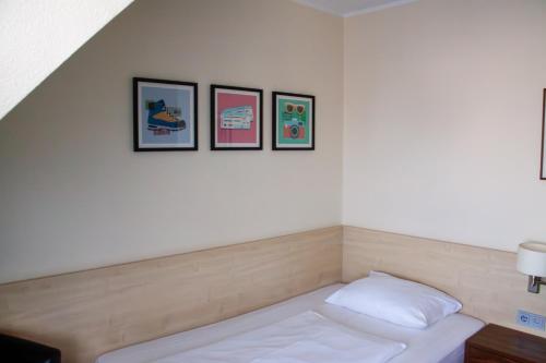 a room with a bed with three pictures on the wall at Garner Hotel Cologne Porz - Airport by IHG in Cologne