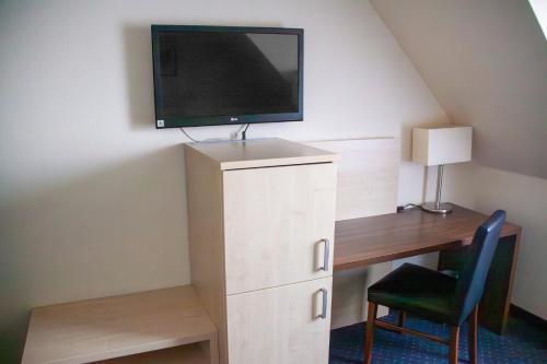 a room with a desk and a tv on a wall at Garner Hotel Cologne Porz - Airport by IHG in Cologne