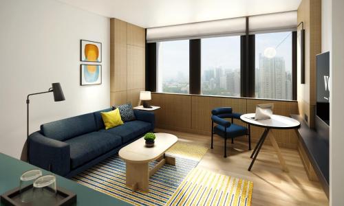 a living room with a blue couch and a table at voco Bangkok Surawong by IHG in Bangkok