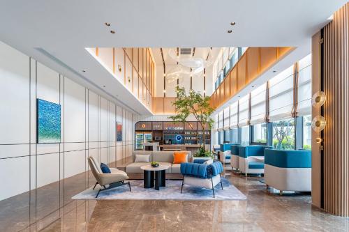 a lobby of a building with chairs and tables at Holiday Inn Express Taizhou Jiaojiang in Taizhou
