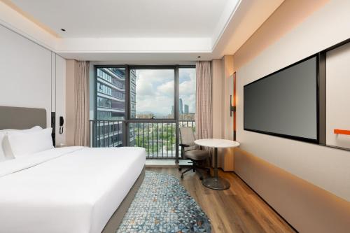 a hotel room with a bed and a flat screen tv at Holiday Inn Express Taizhou Jiaojiang in Taizhou