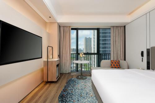 a hotel room with a bed and a flat screen tv at Holiday Inn Express Taizhou Jiaojiang in Taizhou