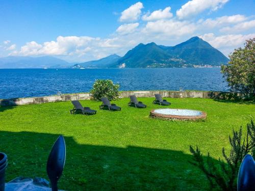 La Villa di Elena في فيربانيا: مجموعة كراسي جالسة على العشب قرب الماء