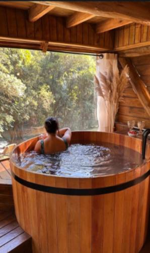 a woman is sitting in a hot tub in a wooden bathtub at Cabanas do Rio in Alfredo Wagner
