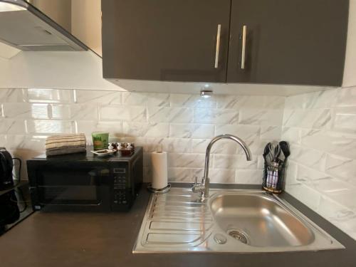 a kitchen counter with a sink and a microwave at Wadham Suites in Liverpool