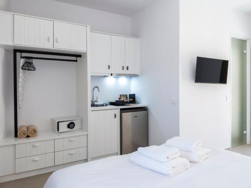 a white room with a bed and a kitchen at Mykonian Shades in Ano Mera