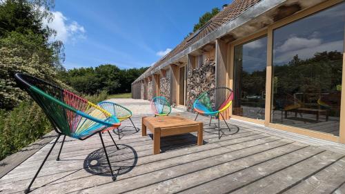 three chairs and a table on a deck at Maison d'architecte, calme et nature réunis in Les Genettes