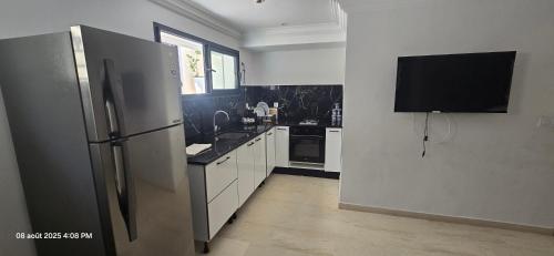 a kitchen with a stainless steel refrigerator and white cabinets at La Brise in Chott Meriem