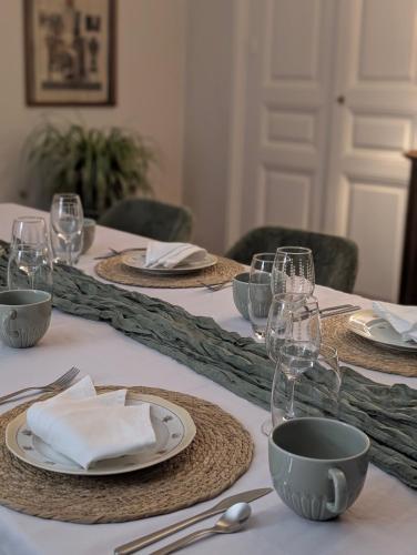 a set of tables with plates and glasses and napkins at La Maison d'Arlette - Maison d'Hôte et Gite au coeur de l'Isère à 10 mn de Voiron, capitale de la Chartreuse, et du Lac de Paladru in Saint-Blaise-du-Buis