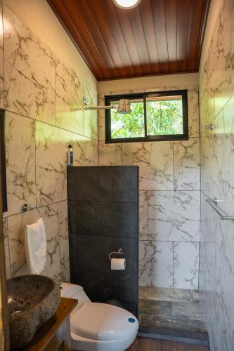 a bathroom with a toilet and a glass shower at Vista Canaan Cabaña de montaña in Rivas