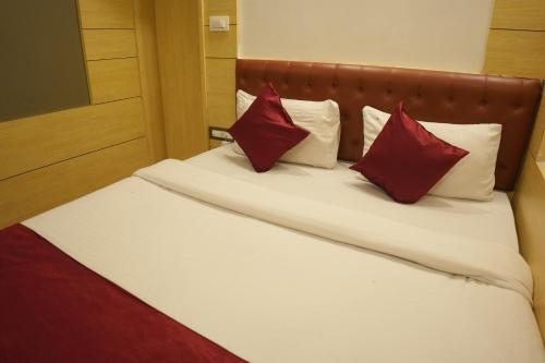 a bed with red and white pillows on it at Hotel Chariot Inn in Deoghar