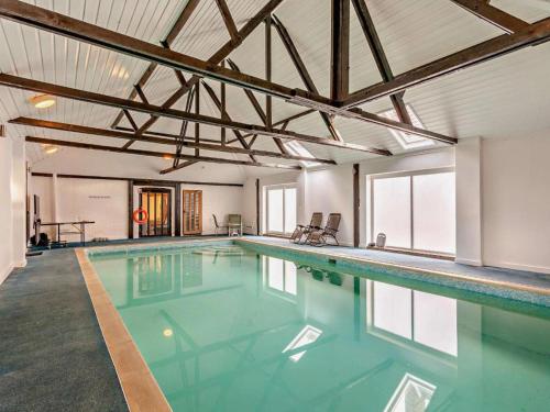 a large swimming pool with blue water in a building at The Pool House - Uk48229 in Tibenham