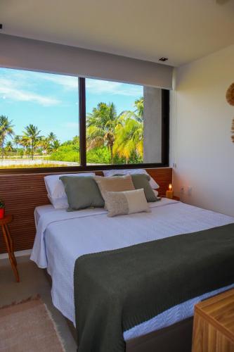 a bedroom with a large bed with a large window at Casa Guaimbê com Rooftop e piscina privativa in São Miguel dos Milagres