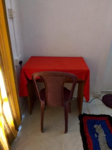a small table with a red table cloth and a chair at Thalalla BnB in Talalla