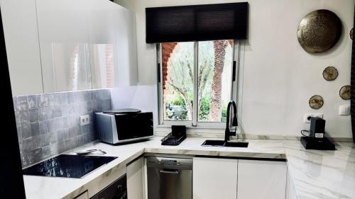 eine weiße Küche mit Mikrowelle und Fenster in der Unterkunft Appart villa de luxe avec 5 piscines in Marrakesch