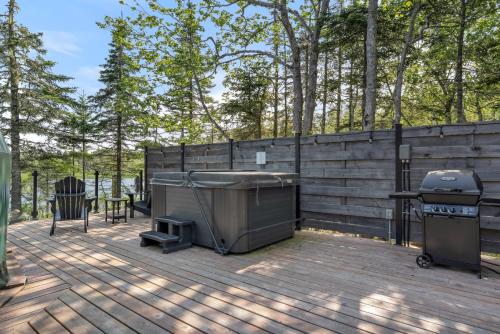 a grill and a tub on a deck with a fence at White Point Beach Resort in Summerville Centre