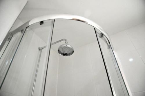 a shower with a glass door with a light at Royal George Hotel in Birmingham