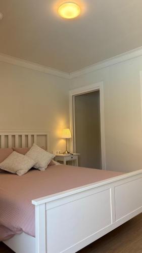 a white bedroom with a large bed with pink sheets at Hotel Antiga in Calafell