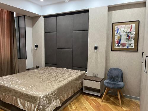 une chambre avec un lit et une chaise bleue dans l'établissement Cozy apartment with all you need, à Bishkek